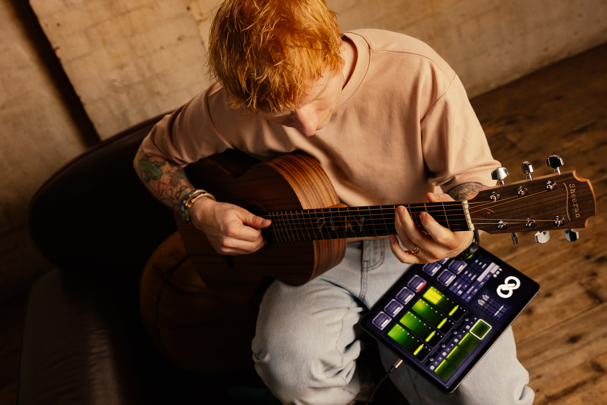 Hands holding an iPad showing the Sheeran Loopy interface with green loop waveforms